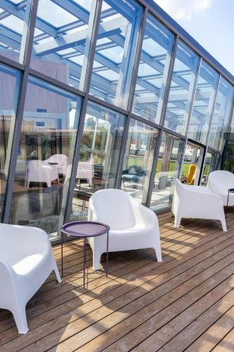 a balcony with white chairs and tables and windows at Luna Self Check-in Hotel Klaipeda in Klaipėda