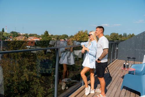 a man and a woman standing on a balcony at Luna Self Check-in Hotel Klaipeda in Klaipėda
