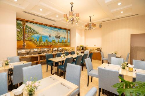 a restaurant with tables and chairs and a painting on the wall at Cap Town Hotel in Ho Chi Minh City