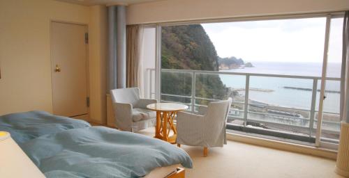 a hotel room with a bed and a large window at Nishiizu Crystal View Hotel in Nishiizu