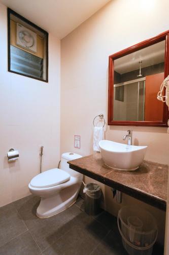 a bathroom with a sink and a toilet and a mirror at MGM Vailankanni in Velānganni