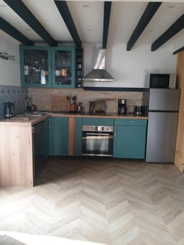 Il comprend une cuisine avec des placards bleus et du parquet. dans l'établissement L'escale du lac, à Saint-Julien-des-Landes