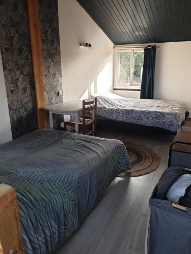 una camera da letto con due letti, un tavolo e una finestra di L'escale du lac a Saint-Julien-des-Landes