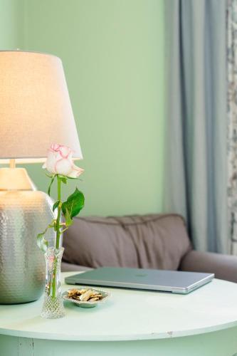 a table with a vase with a flower and a laptop on it at Orkla Gjestebolig in Løkken