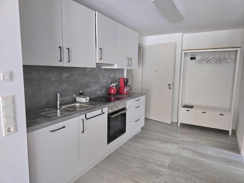 a kitchen with white cabinets and a sink at Ferienwohnungen Miller in Saarburg