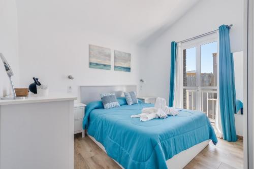 Un dormitorio con una cama con sábanas azules y una ventana. en Home2Book Green Oasis Charming Duplex Maspalomas, en Maspalomas
