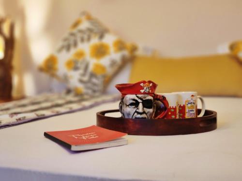 a cup with a pirate face on it next to a book at Rashmi Cottage - 4 BHK Villa with Serene Valley Views in Dagshai
