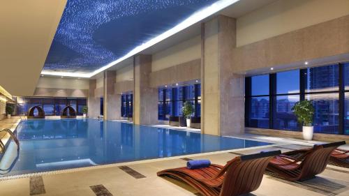 a large swimming pool with two chairs and a swimming pool at Crowne Plaza Yibin by IHG in Yibin