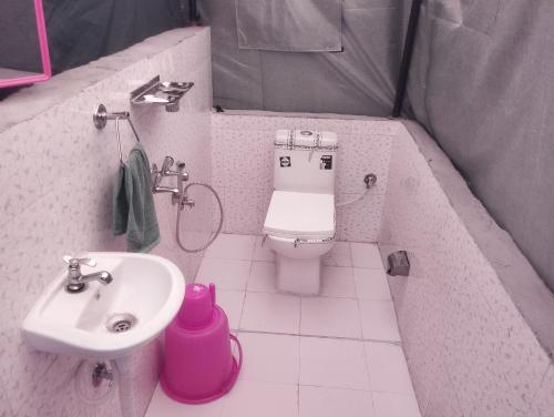 a small bathroom with a toilet and a sink at Tree Bones Camp in Bīr