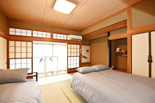 a bedroom with two beds and a large window at The house of calmness in Beppu