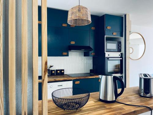 - une cuisine avec des placards bleus et une table avec une bouilloire dans l'établissement Pinède, plage et billard, à La Rudelière