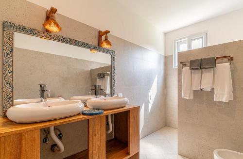 a bathroom with two sinks and a large mirror at Maharaja Boutique Hotel Zanzibar in Uroa