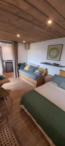 Cette grande chambre comprend deux lits et une table. dans l'établissement Cabane en bois au calme, à Saint-Romain-de-Benet