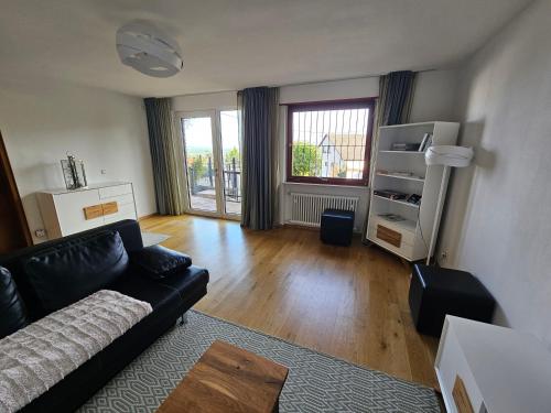 a living room with a black couch and a wooden floor at Ferienwohnung Sieben Raben in Neustadt an der Weinstraße