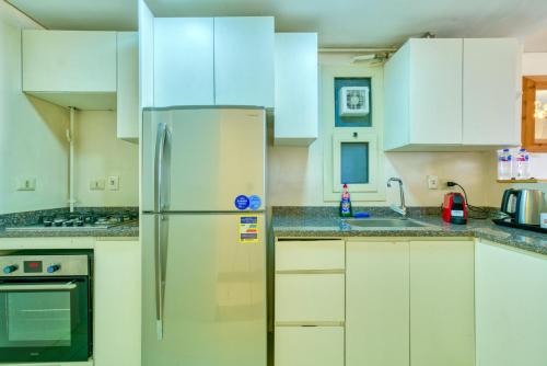 a kitchen with white cabinets and a refrigerator at LOFTS by Elegant Hospitality in Cairo