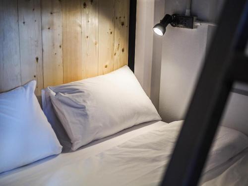 a bed with a white pillow and a wooden wall at THE BEST ONE CHIANG MAI in Chiang Mai