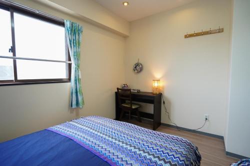 a bedroom with a bed and a desk and a window at 餘軒 名古屋駅アクセス便利 セルフチェックイン in Minami-sotoborichō