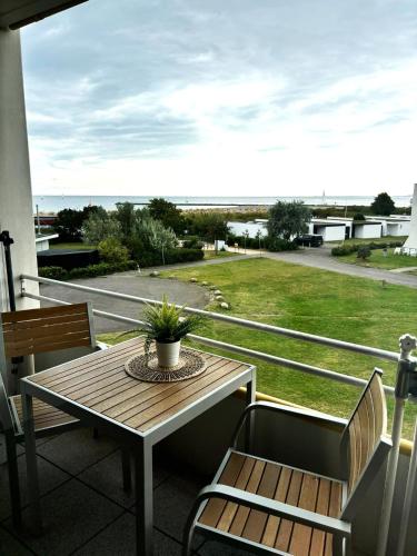 a table and chairs on a balcony with a view of the ocean at Quartier Südstrand - Ferienwohnung mit Meerblick in Fehmarn