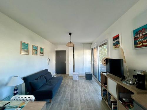 un salon avec un canapé bleu et une télévision dans l'établissement Ma Mika - Appartement proche mer, à Saint-Nazaire