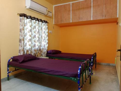 two beds in a room with a window at Square & Dormitory Stays in Tirunelveli