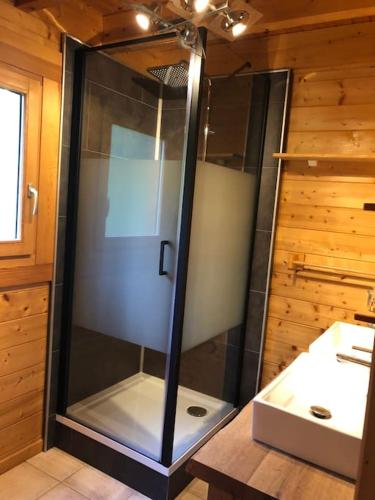 une douche en verre dans une salle de bain avec un lavabo dans l'établissement Chalet les Minés - Hautes Vosges, à Plainfaing