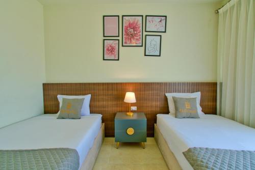 two beds in a room with a nightstand between them at LOFTS by Elegant Hospitality in Cairo