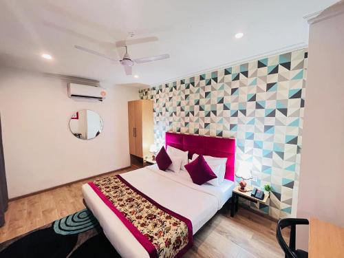a bedroom with a large bed with a red headboard at Qotel Comfort Chattarpur - Opposite Tivoli Garden Near Chattarpur Metro in New Delhi