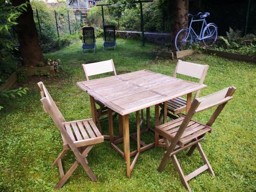 una mesa de madera y 4 sillas en un patio en Rez de jardin en bordure de ruisseau, en Le Bonhomme