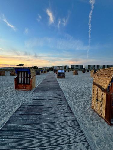 a wooden walkway on a beach with chairs on it at Quartier Südstrand - Ferienwohnung mit Meerblick in Fehmarn