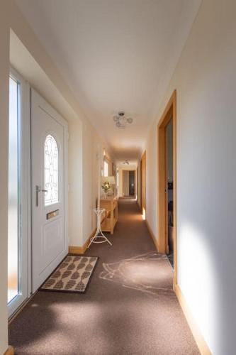 an empty hallway with a white door and a room at Bungalow with Hot Tub, BBQ Hut, Golf Net , Large Garden & Play Area in Maybole