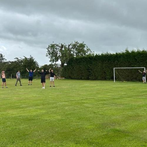 a group of people standing in a field playing frisbee at Bungalow with Hot Tub, BBQ Hut, Golf Net , Large Garden & Play Area in Maybole