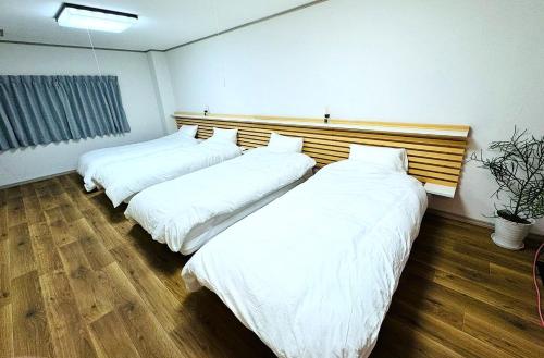 two beds in a room with white sheets at ゲストハウスサンパティオ in Shingu