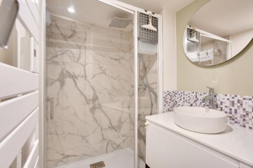 une salle de bain blanche avec un lavabo et une douche dans l'établissement 250m de la plage - Studio pour 2 - Balcon, à Dinard