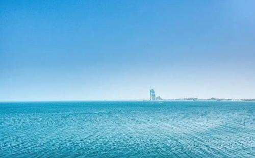 a large body of water with a building in the distance at Luxury Holiday Home, Spacious 1 bedroom, Burj Alarab full ocean view, located in Anantara the palm, Palm Jumeirah, Dubai in Dubai