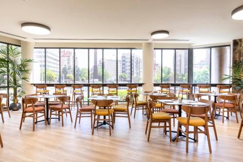 a restaurant with tables and chairs and large windows at Acta Pirámides in Madrid