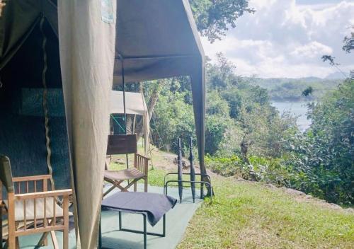 a porch of a house with chairs and an umbrella at Belihuloya Adventure Camp By Eco Team in Belihul Oya