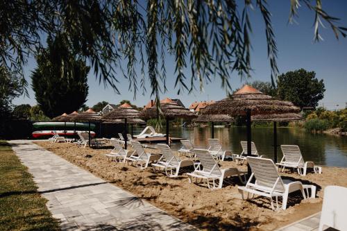 a group of chairs and umbrellas on a beach at Füzeskerti Apartmanház in Békésszentandrás