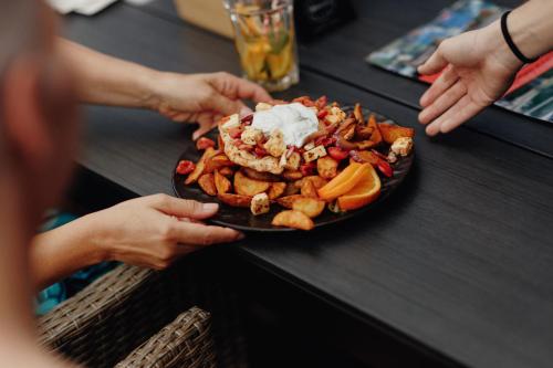 a person holding a plate of food on a table at Füzeskerti Apartmanház in Békésszentandrás