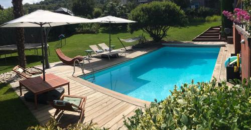- une piscine avec des chaises et des parasols sur une terrasse en bois dans l'établissement Gîte avec piscine chauffée & aires de jeux pour enfants, à Barberaz