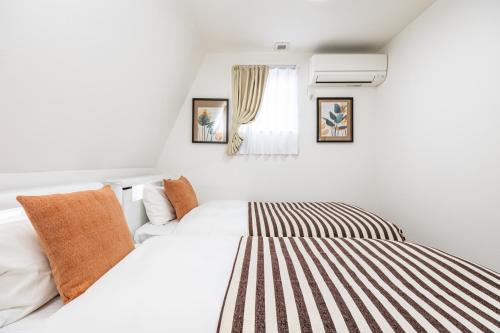 a white bedroom with a bed and a window at Modern Japan 東京浅草 east in Tokyo