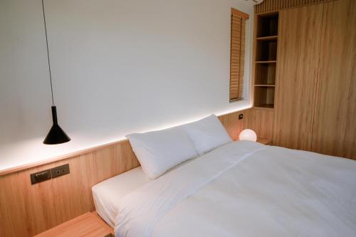 a bedroom with a bed with white sheets and a lamp at Ikigai Retreat Moc Chau in Mộc Châu