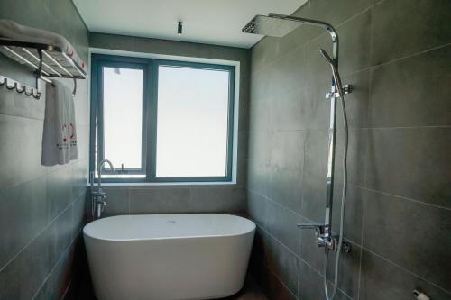a bathroom with a bath tub and a window at Ikigai Retreat Moc Chau in Mộc Châu