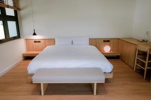 a bedroom with a white bed with a bench in it at Ikigai Retreat Moc Chau in Mộc Châu