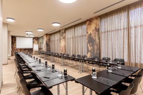 a conference room with tables and chairs and a screen at Acta Pirámides in Madrid