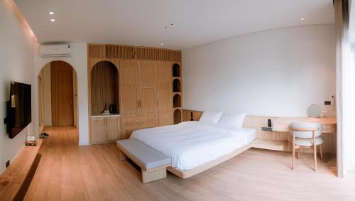 a bedroom with a large white bed and a desk at Ikigai Retreat Moc Chau in Mộc Châu