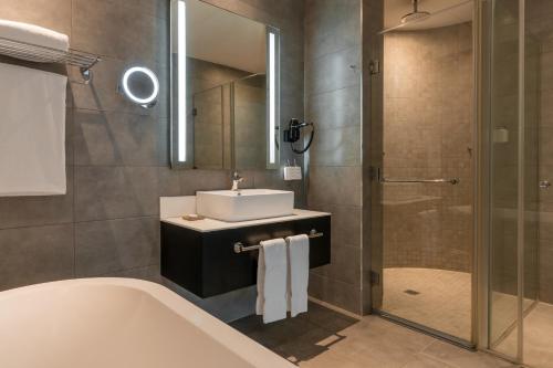 a bathroom with a sink and a tub and a shower at Radisson Lagos Ikeja in Lagos