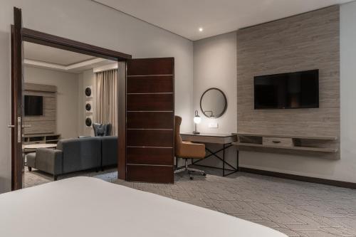 a hotel room with a bed and a desk and a tv at Radisson Lagos Ikeja in Lagos