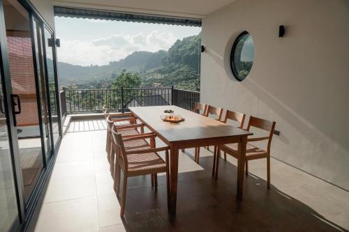 a dining room with a table and chairs on a balcony at Ikigai Retreat Moc Chau in Mộc Châu