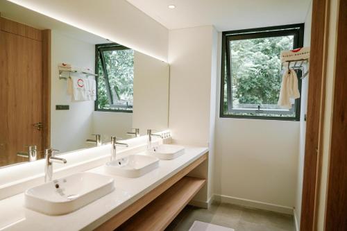 a bathroom with three sinks and a large mirror at Ikigai Retreat Moc Chau in Mộc Châu