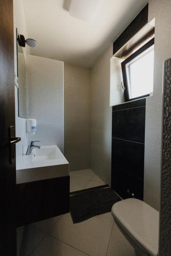 a bathroom with a sink and a toilet and a window at Misúr Vendégház in Békésszentandrás